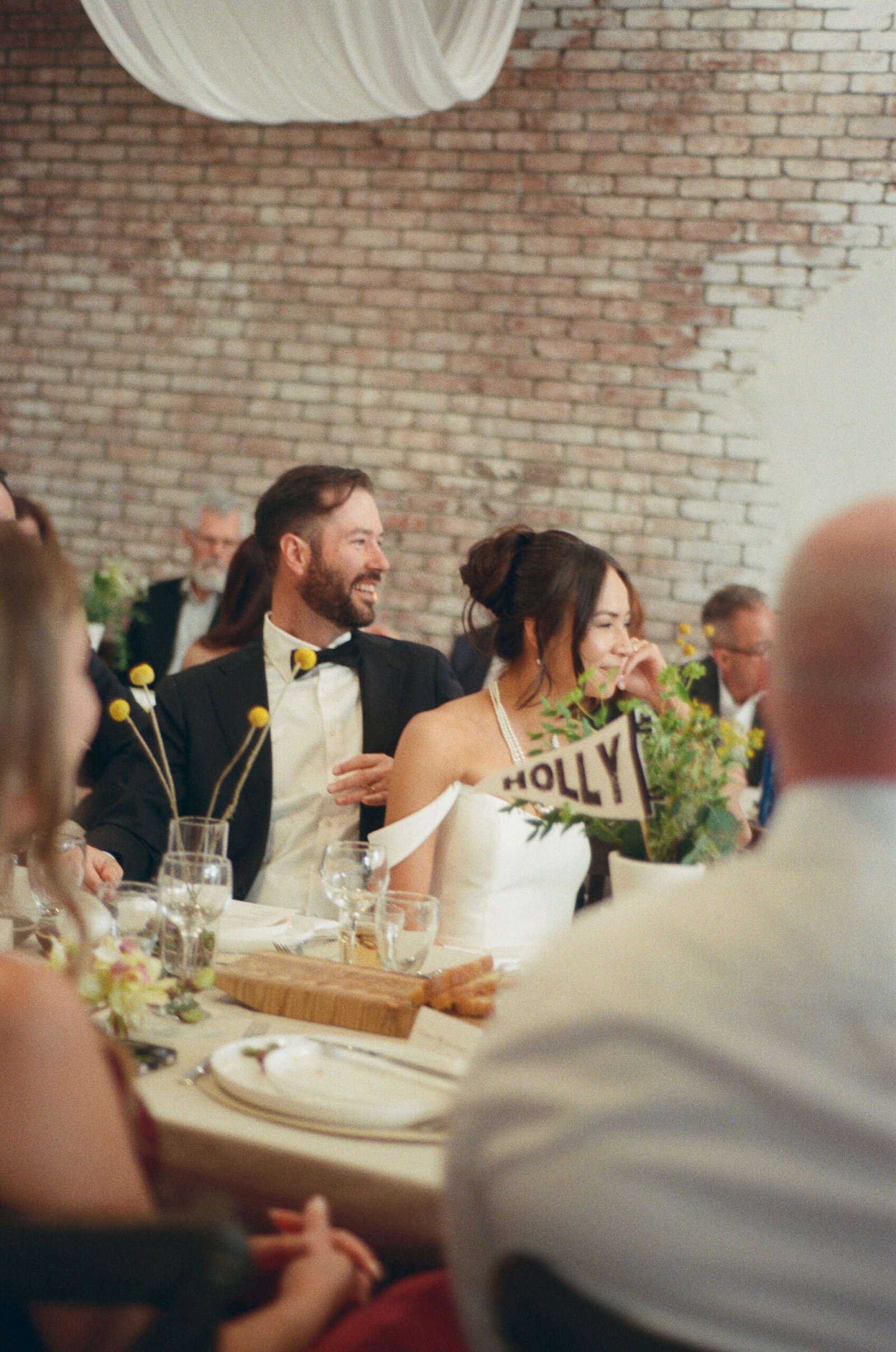 Happy bride and groom at their DIY wedding reception table with floral centerpieces.
