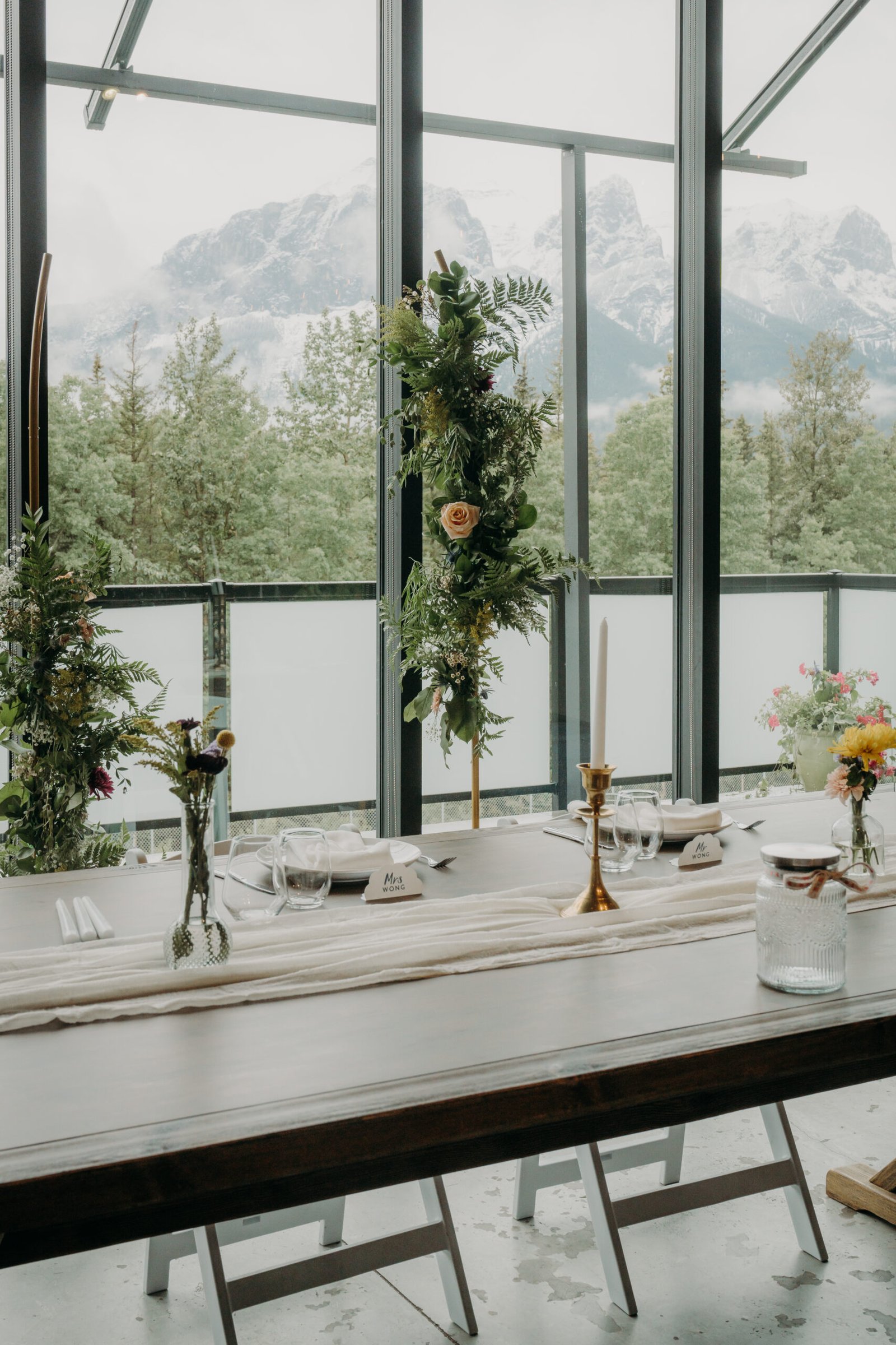 Indoor wedding reception setup with mountain views through floor-to-ceiling glass windows.